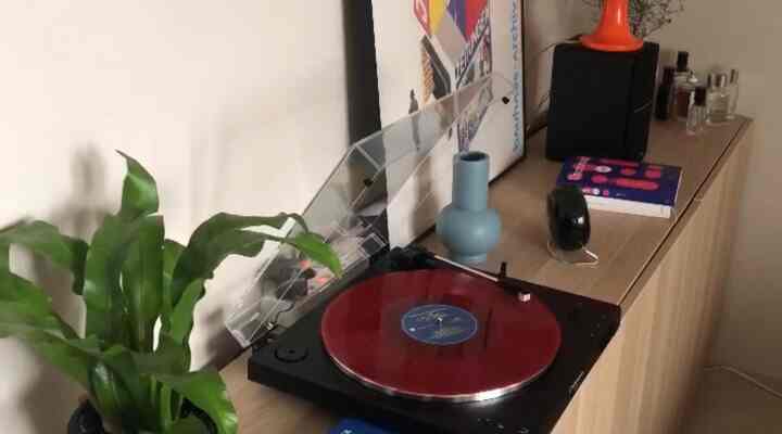 ライトブラウンの木目調の棚と赤いLPが置かれたターンテーブルのある雰囲気のある寝室