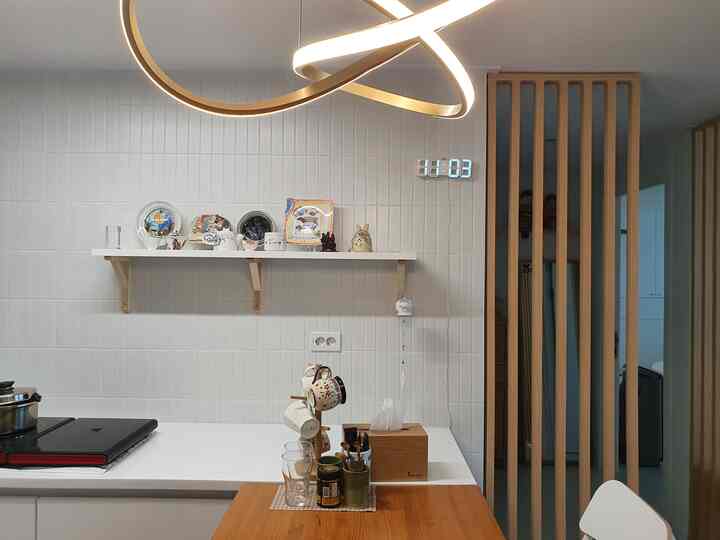 White tiled kitchen wall with wooden table and a shelf replacing upper cabinets, creating a clean kitchen space