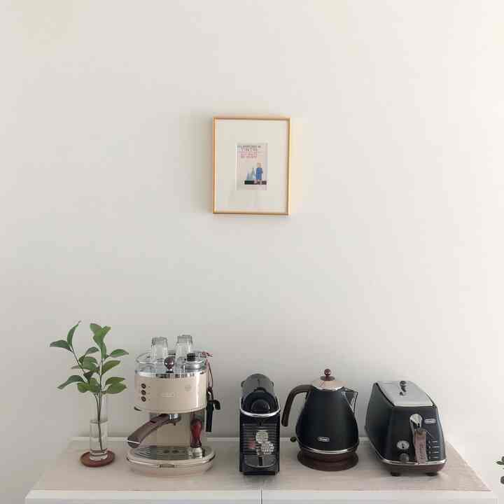 白を基調としたキッチン、中央にデロンギのコーヒーマシン、トースター、ケトルが整然と配置されたおうちカフェのインテリア