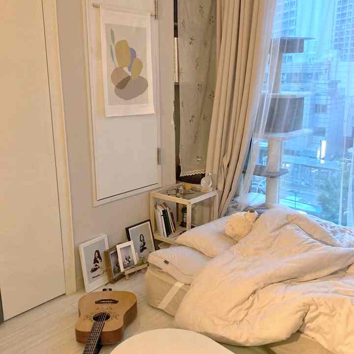Cozy bedroom space in warm beige tones featuring pillows, bedding, wood nightstand and curtains