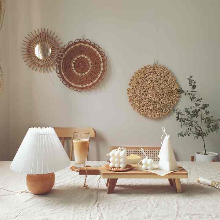 ナチュラルな木目調とラタン小物が調和するシンプルなおうちカフェ空間、テーブルの上にはアイスラテと個性的な形のキャンドルが配置されている