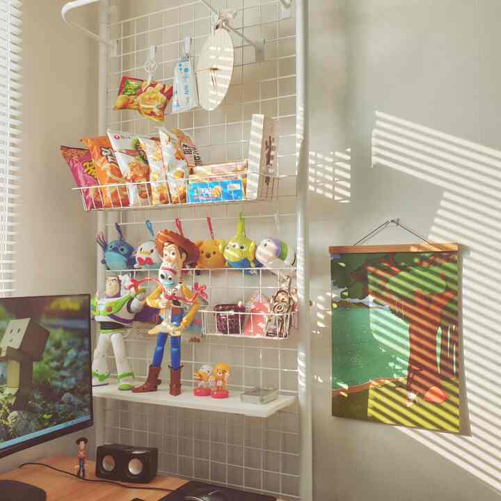 White-toned study space with partition, featuring Toy Story figures and snacks arranged around a cozy computer desk
