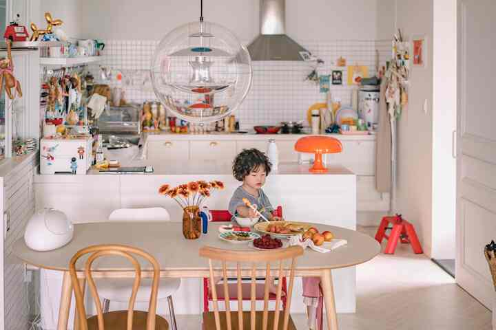 白を基調としたキッチン、ダイニングテーブルで座る子供とキッチンアイランドが印象的な雰囲気のあるインテリア