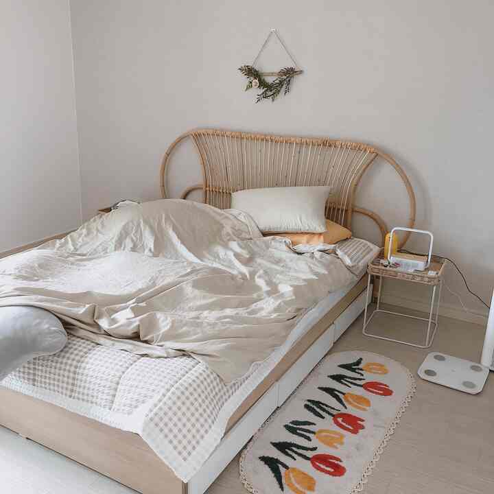 ベージュとナチュラルカラーの寝室、ラタンヘッドボードのベッドとナイトテーブルが配置された雰囲気のあるインテリア