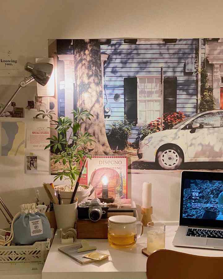 Brown and white toned workspace featuring desk with laptop, lighting, and a poster creating a cozy atmosphere