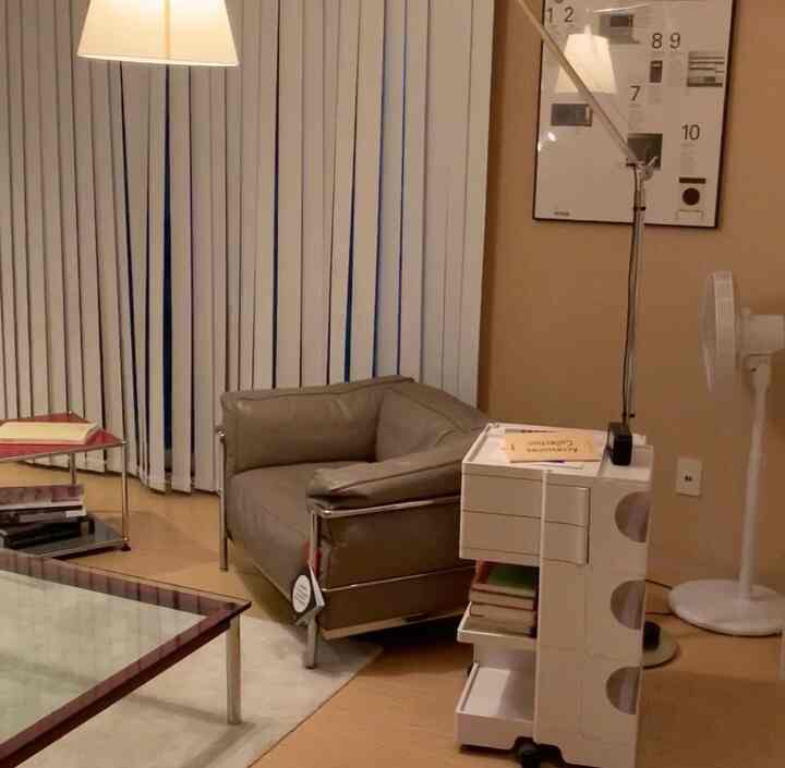 Modern living room with white vertical blinds and brown leather armchair, featuring clean and cozy atmosphere