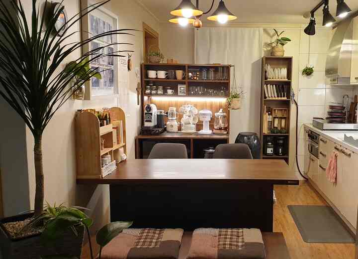 温かみのあるウッドトーンとナチュラルカラーのキッチン兼おうちカフェ、カフェマシンとダイニングテーブルが配置された居心地の良い空間