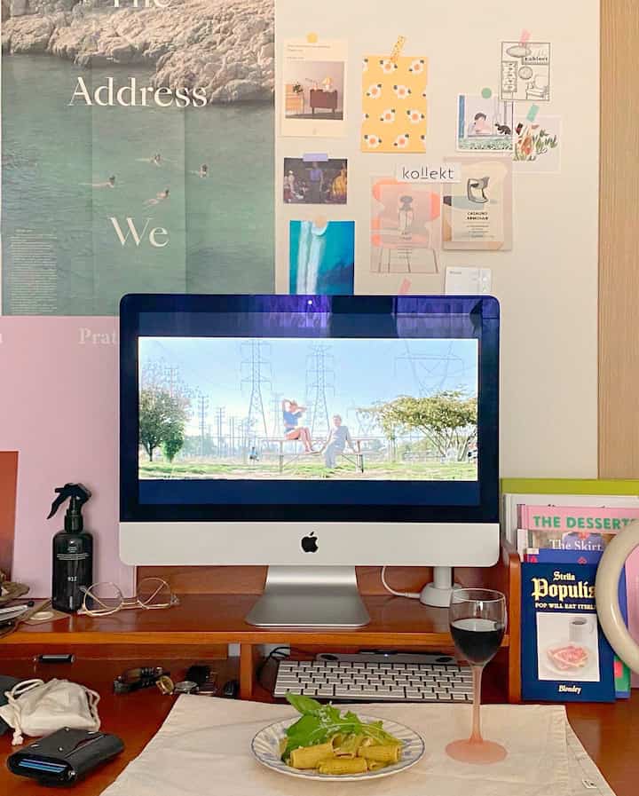 Natural wood-toned studio workspace featuring a desk, wine glass, and monitor playing a movie creating cozy home cafe vibe