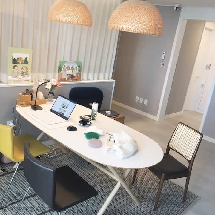 Bright white-toned dining room featuring rattan pendant lights and various colored chairs, with a modern natural interior design