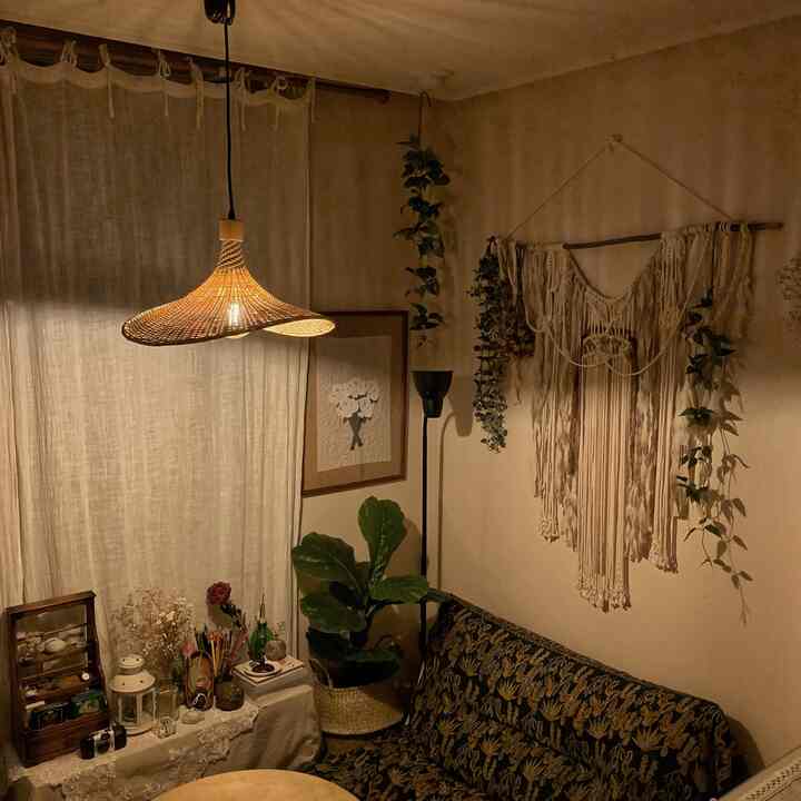 温かみのあるベージュとブラウンのリビング、マクラメの壁飾りと自然素材の照明が配置されたナチュラルでボヘミアンな雰囲気のインテリア