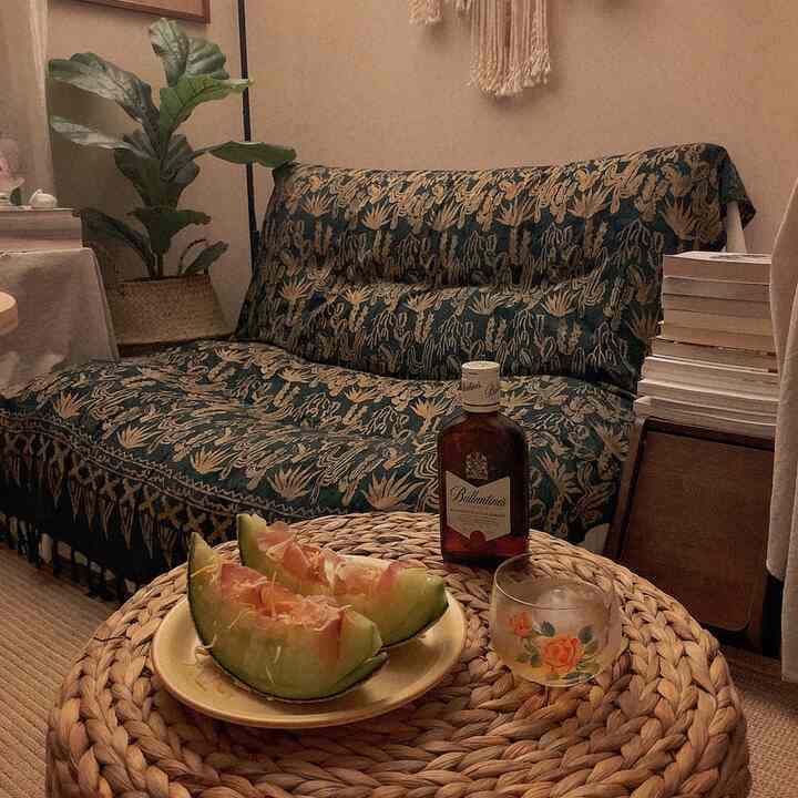 ナチュラルカラーとグリーンの調和が美しいリビング、柄入りのソファとラタンテーブルが温かみのある居心地の良いインテリア