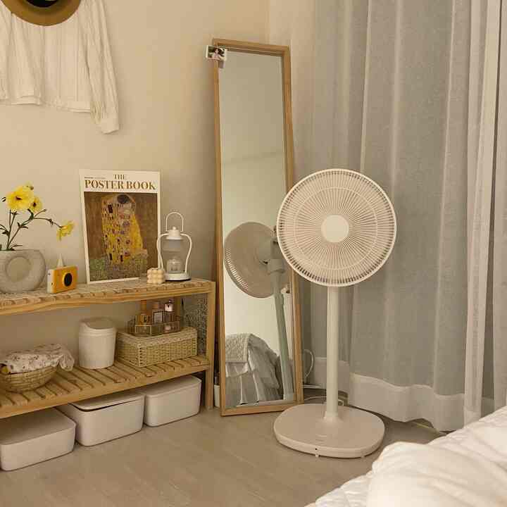 白と木目調の狭い寝室、全身鏡と扇風機、木製棚が配置された雰囲気のあるナチュラルモダンな空間