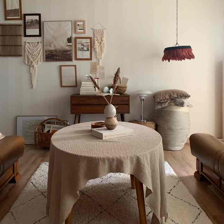 ベージュと木目調が調和したスカンジナビア風のリビング、丸テーブルと化粧台が配置されたナチュラルな空間