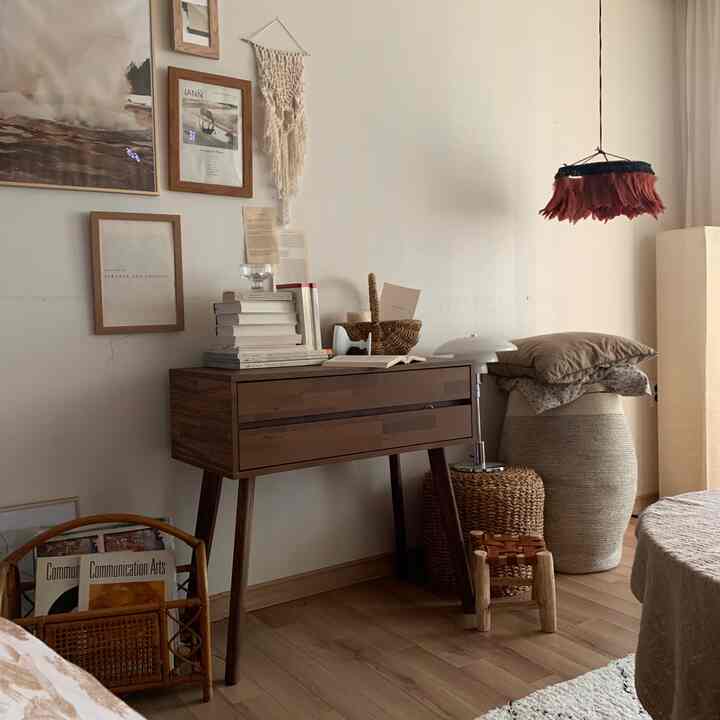 Brown and natural tone living room corner featuring a wooden vanity console, wall art, and natural decor creating a cozy atmosphere