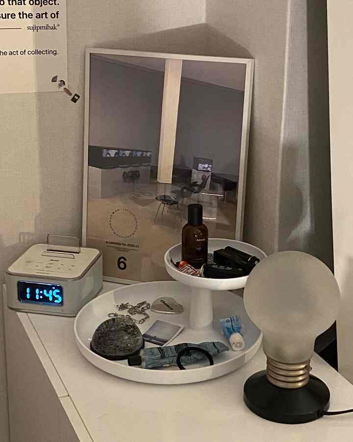 白と黒の色調のナイトテーブルにテーブルランプとトレイが置かれたミニマルな空間