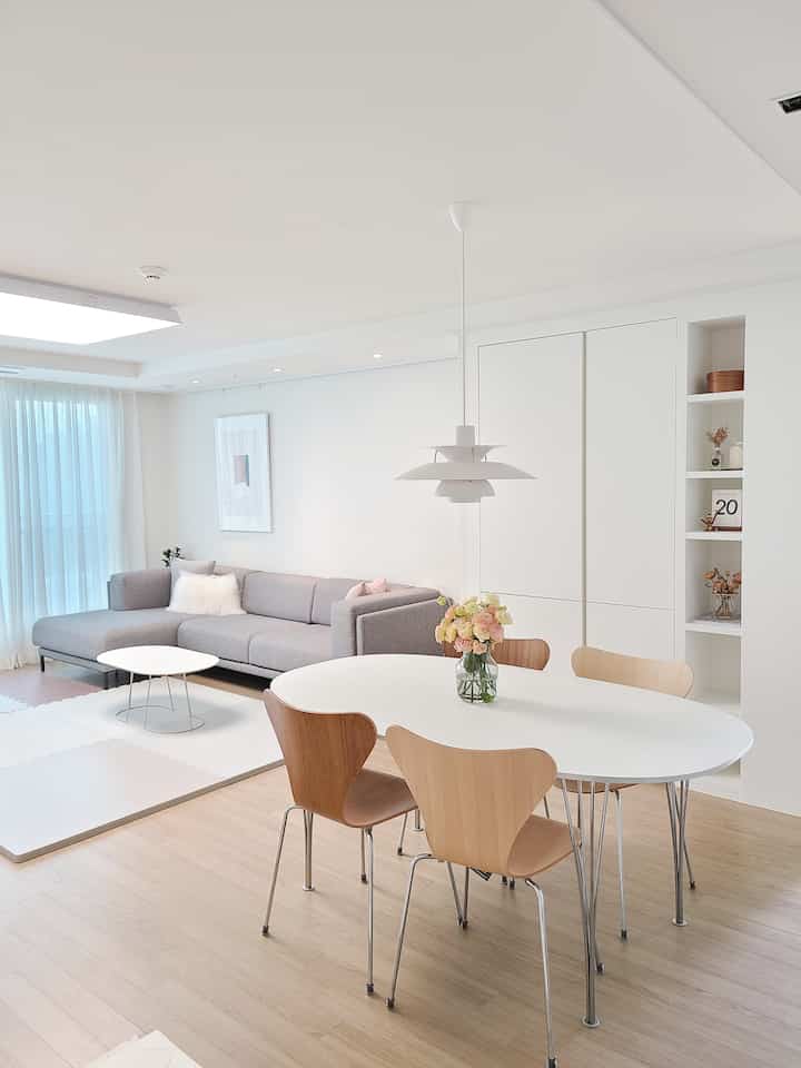 A simple modern living and dining room in white and natural tones with clean-lined furniture