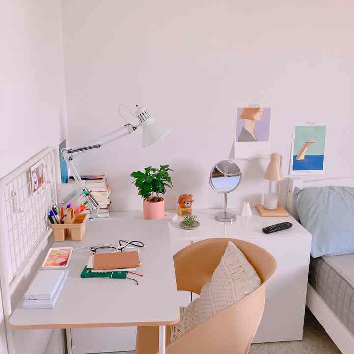 Bright white walls with beige armchair, desk lamp, and desk in a simple natural single household home office setup