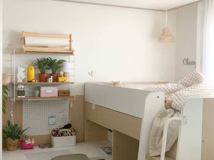 Natural tone kids' room featuring white and beige bunk bed with checkered bedding and a rattan lampshade, creating a warm atmosphere