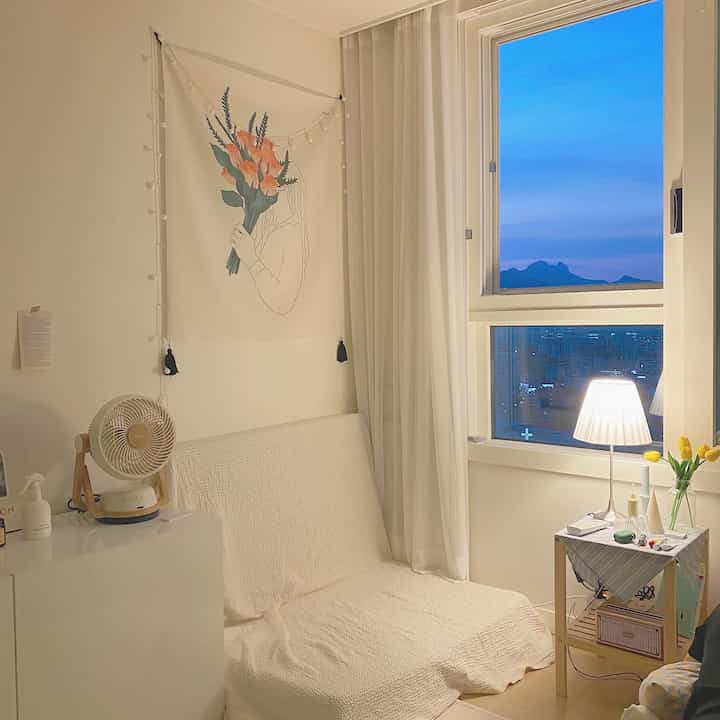 白と木目調が調和する居心地の良いリビング、折りたたみマットレスソファとフロアランプが配置された自然なインテリア