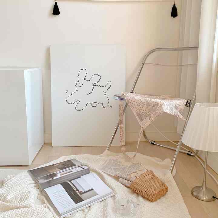 Cream-toned living room with transparent furniture, featuring a cute illustrated picture frame and folding chair in a cozy setting