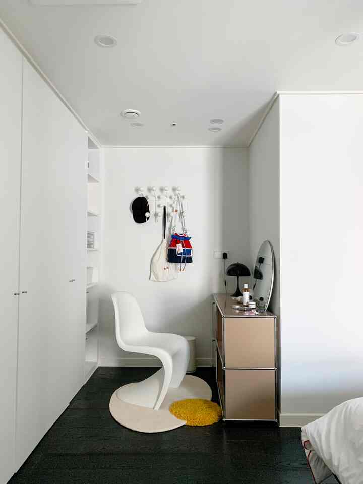 A neat white and beige bedroom featuring a Panton chair and USM sideboard with minimalistic design