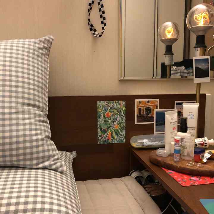 Beige and brown toned bedroom featuring checkered pillow and vanity desk with cozy atmosphere