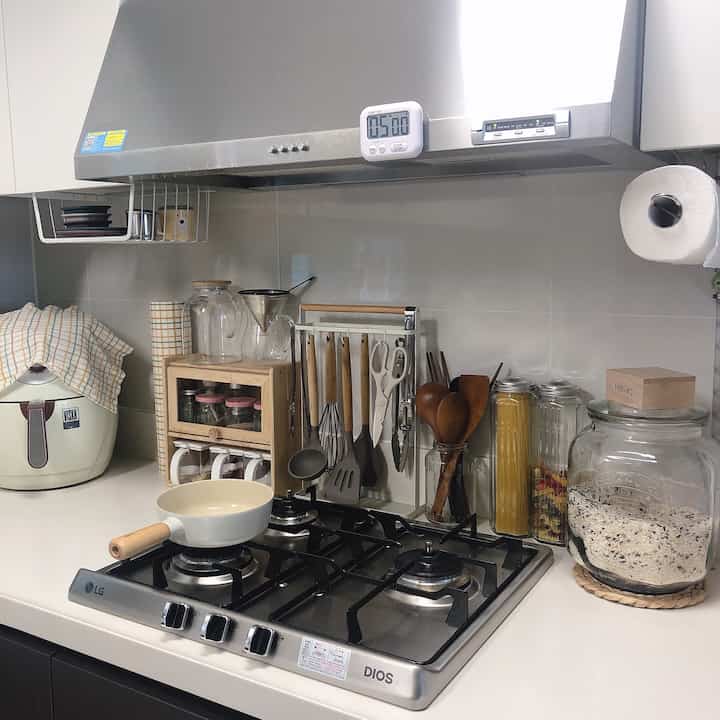 ナチュラルな木目調と透明なガラスが調和した、調理器具とガスコンロが配置された清潔なキッチン