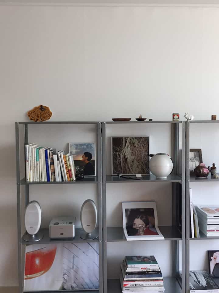 Natural style living room with white walls and gray metal shelving filled with books and decorative items