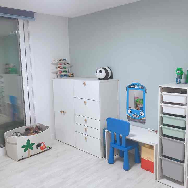 White and blue toned kids' room featuring a desk and storage cabinets with a clean and cozy atmosphere