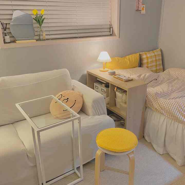 Studio apartment bedroom with bright sky blue walls and yellow cushions and stool, creating a cozy atmosphere