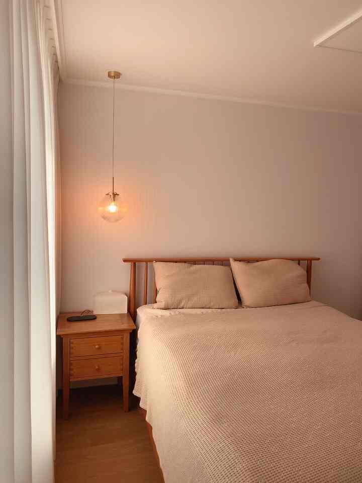 Beige-toned bedroom featuring wood bed and nightstand with pendant light creating cozy atmosphere