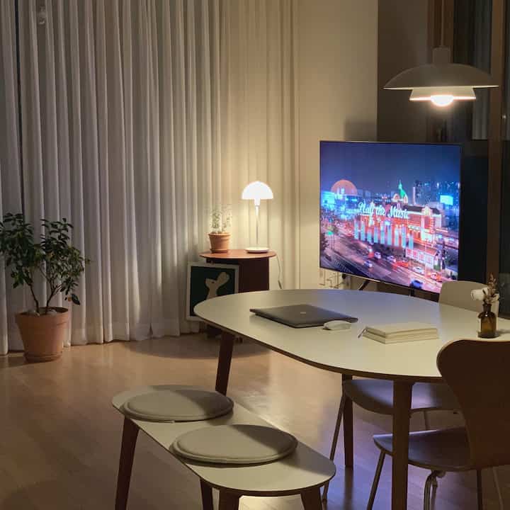 White and natural brown toned living room featuring a dining table with pendant and table lamps creating a cozy atmosphere