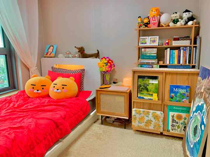 Cozy bedroom with warm wood tones and vivid red bedding, featuring Ryan character plush toys and charming small decorative items