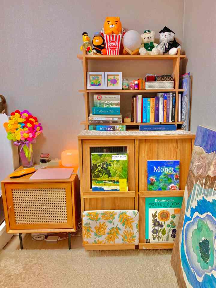 ナチュラルウッド調の小さな書斎空間、本棚とポスターがかわいく配置された居心地の良い読書と作業スペース