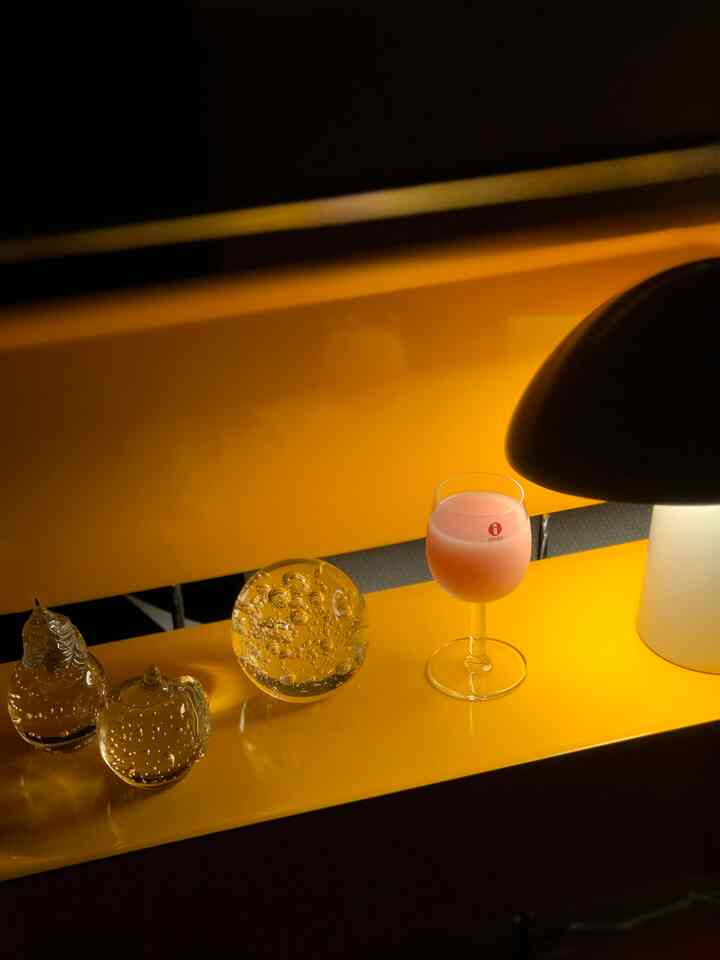 Cozy bedroom interior accessories featuring bright yellow trolley with glass objets, wine glass, and table lamp