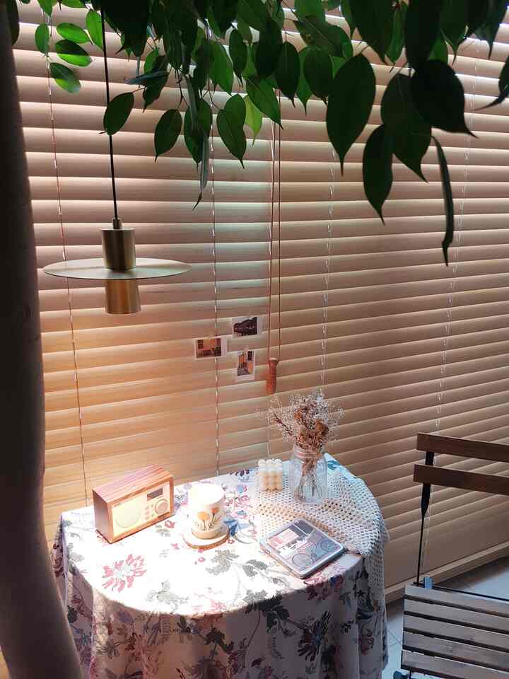 Cozy balcony home cafe space featuring brown wood blinds and wooden chair with soft pendant lighting.