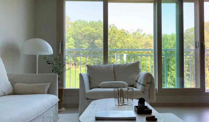 White and natural toned living room featuring cozy sofas and marble coffee table with serene atmosphere