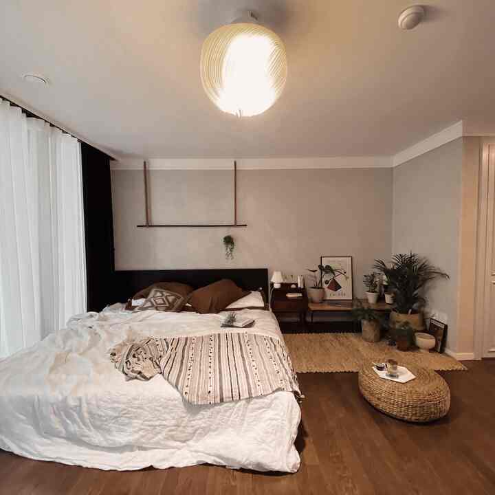 Natural-colored and wood-toned bedroom featuring rattan stool and plants with a cozy and warm atmosphere