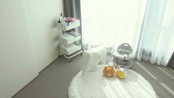White and ivory toned kids' room featuring a round rug, elephant stool, and baby chair in a clean, bright space