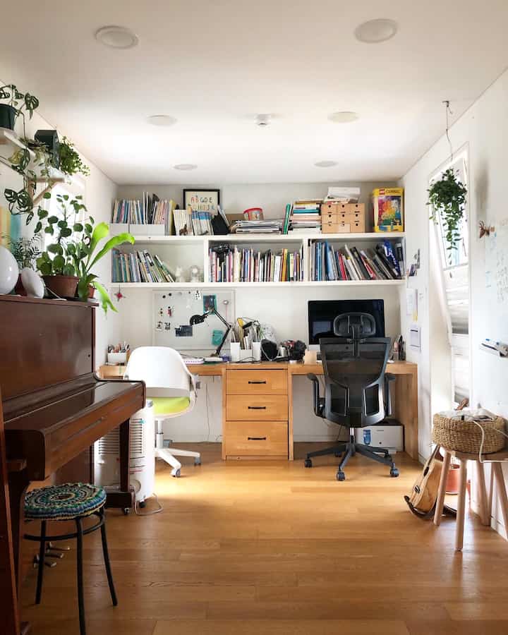 White and brown toned loft living room converted into a study room featuring custom desks and bookshelves in a neat home office