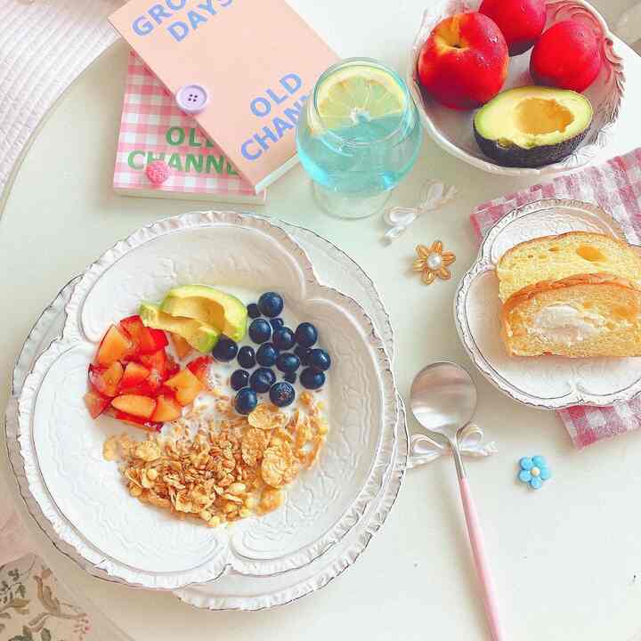Cozy home cafe brunch space with cereal, fruits, and cream bread on a white dining table