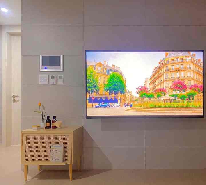 ホワイトとウッド調が調和したリビング、壁掛けテレビとサイドテーブルが配置された雰囲気ある空間