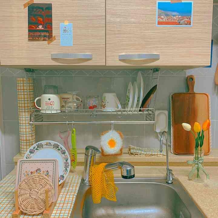 木目調とナチュラルな雰囲気のキッチン、シンクの上に食器や調理器具が整頓された印象的な空間