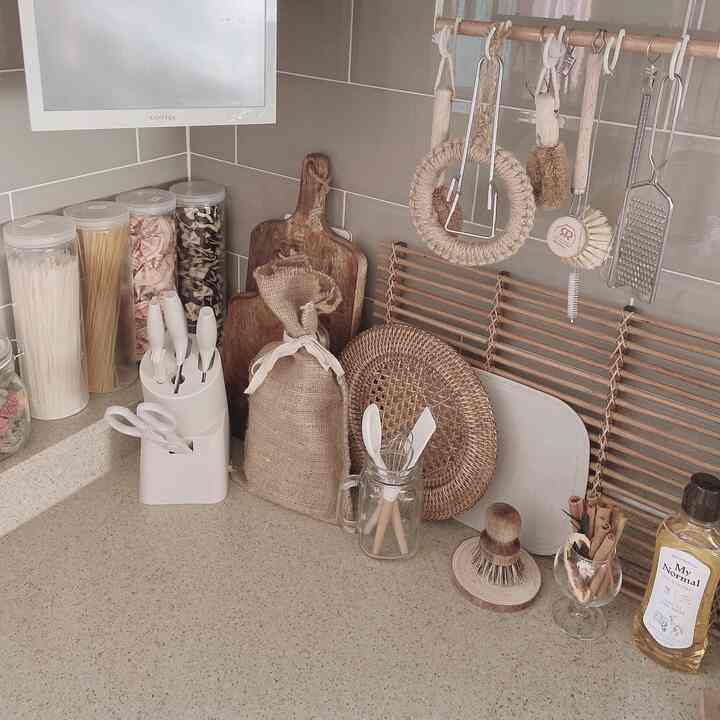 ベージュとナチュラルカラーのキッチンコーナー、包丁セットやラタンのトレイ、さまざまな調理器具が整然と配置された雰囲気のあるインテリア