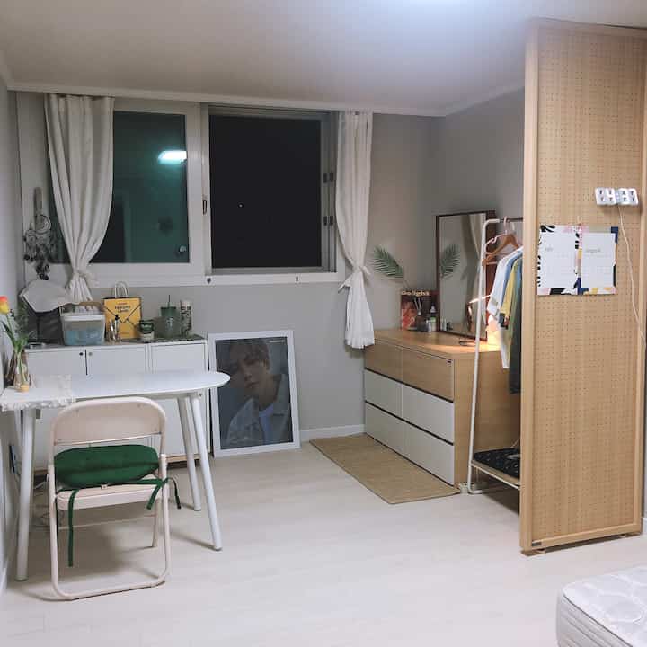 白と木目調の狭い寝室、デスクとドレッサーが配置されたシンプルな学生部屋のインテリア