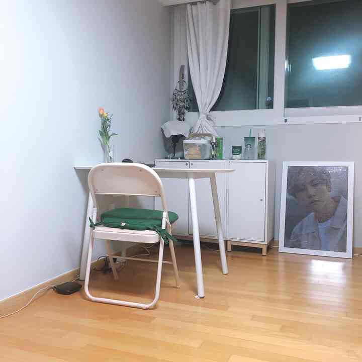 Natural and white toned studio workspace featuring a simple desk and folding chair with a cozy atmosphere