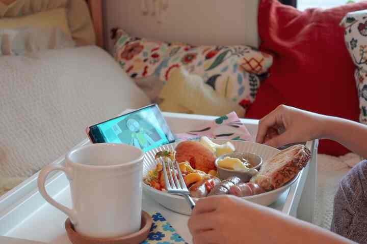 ホワイトとナチュラルカラーの寝室、ベッドトレイにカップと皿が置かれた雰囲気のあるインテリア