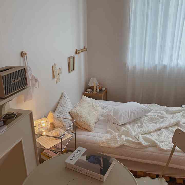 White and beige toned studio bedroom featuring pillows and nightstand in a cozy, natural atmosphere