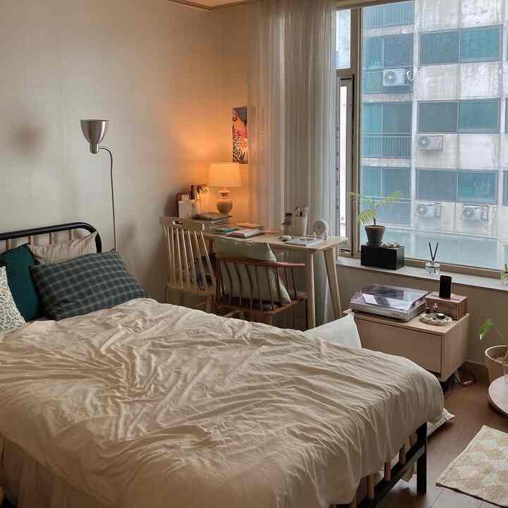 Beige and natural toned studio bedroom featuring a bed and desk placed by the window, creating a cozy atmosphere