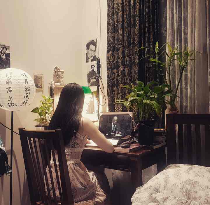 Cozy wood-toned bedroom home office for a single person, featuring plants and a Japanese-style lamp on the desk with warm lighting